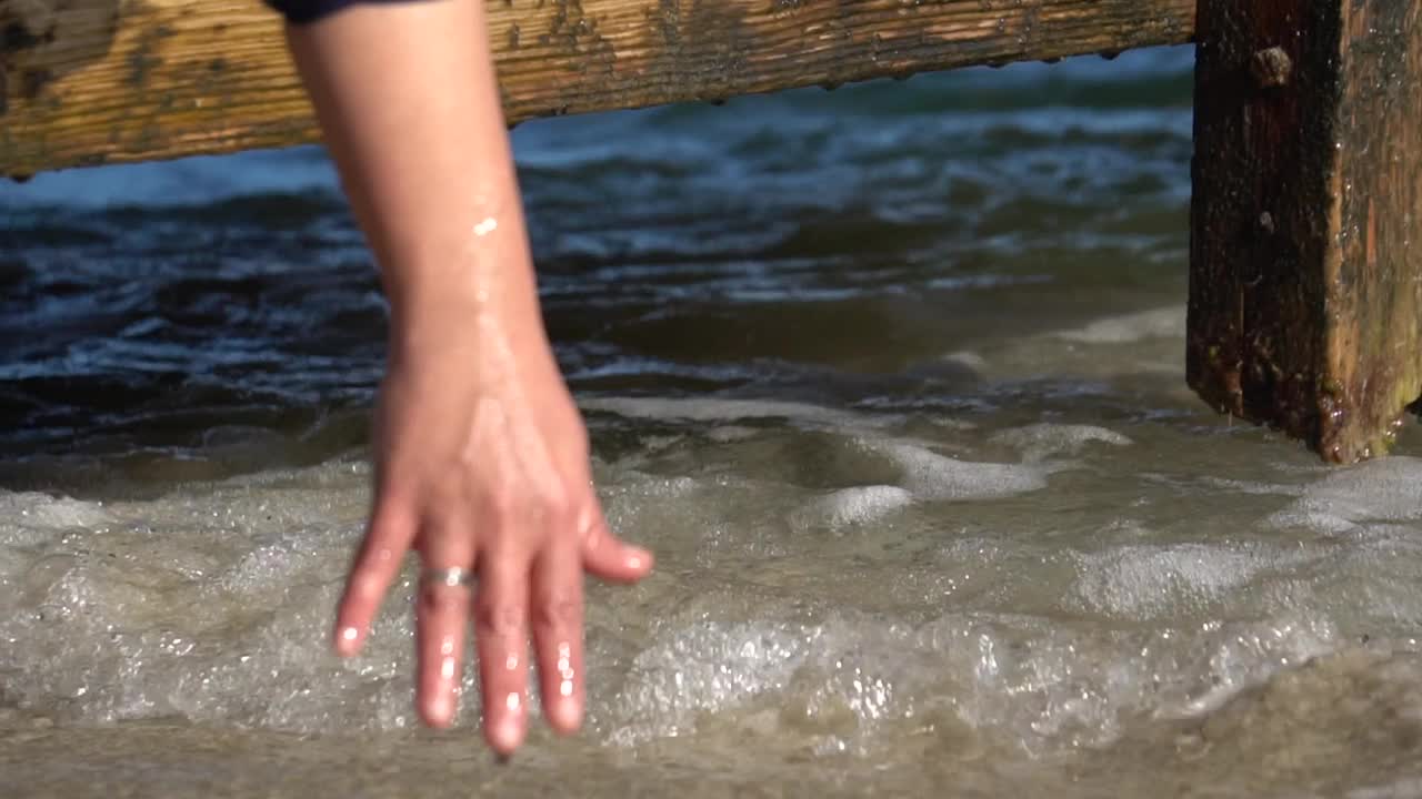 在一个阳光明媚的日子里，女人在甲板上与海浪玩耍视频下载