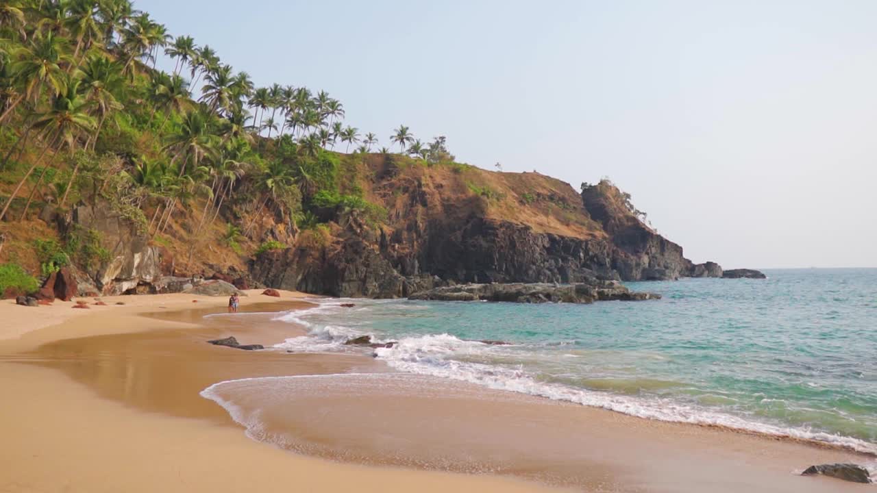 印度果阿Kakolem海滩海岸的海浪。海滩上的海浪，自然的夏日背景。印度的热带海滩。棕榈树海滩和蓝色的大海在夏天的时候。视频素材