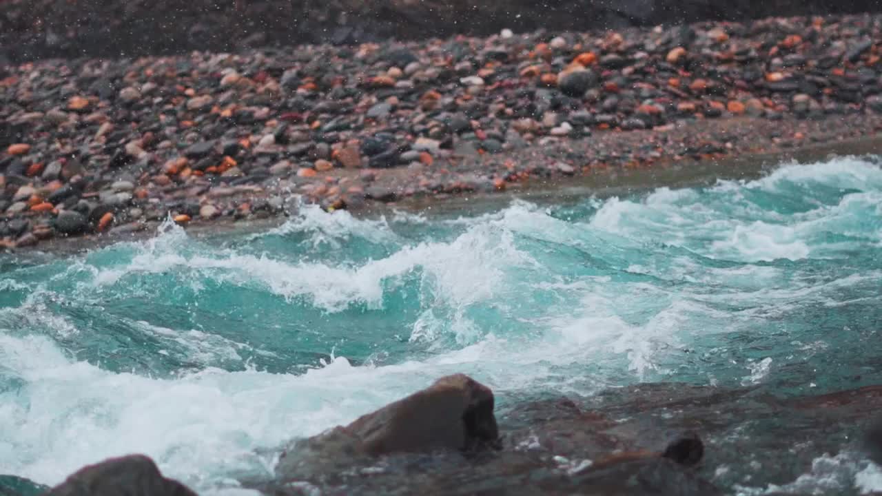 在印度喜马偕尔邦的西苏，钱德拉河在降雪期间在山脉之间流动的慢镜头。喜马拉雅山脉降雪期间蓝色蓝绿色河流的缓慢运动。视频素材