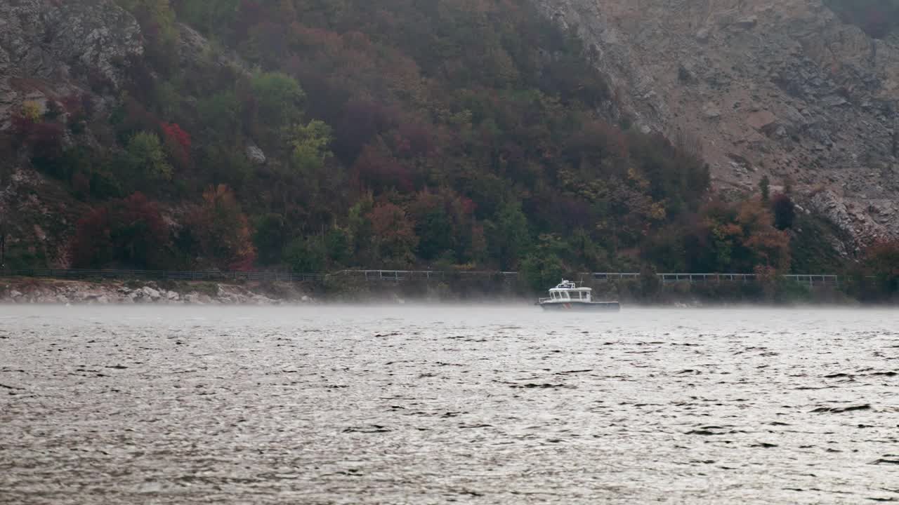 一艘小河船漂浮在雾气弥漫的河面上，背景是群山视频素材