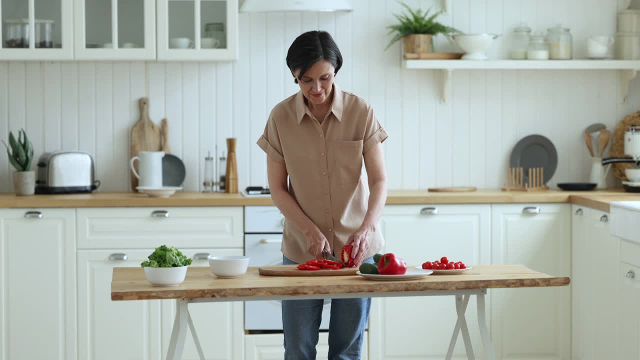 迷人的中年妇女切红辣椒准备素食沙拉视频素材