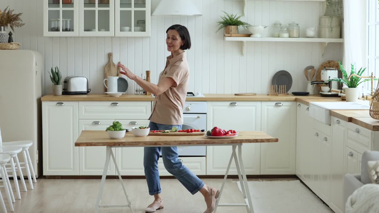 女人一边听着最喜欢的音乐，一边忙着做素食沙拉视频素材