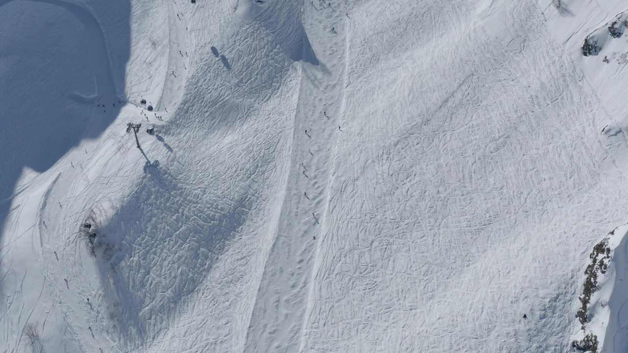 顶视图滑雪者，游客骑在坡下冬季滑雪场轨道顶部拍摄视频素材