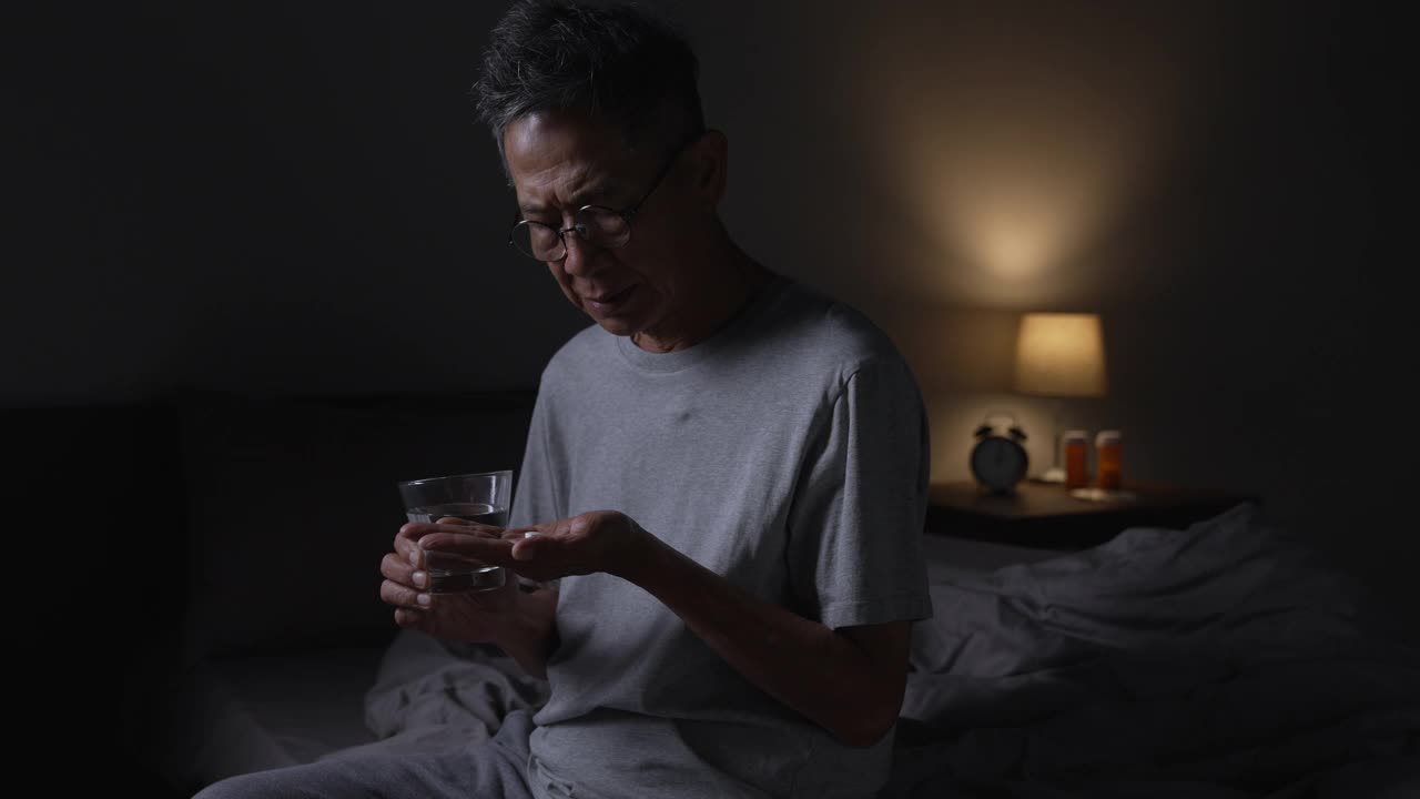 抑郁的亚洲老年男子因失眠而无法入睡。高级亚洲男子服用安眠药。视频素材