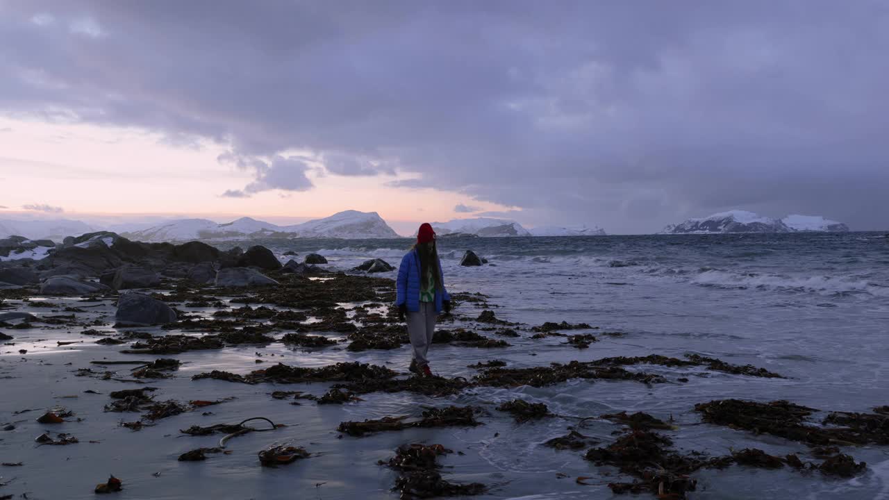 挪威，日落时分，一名女子在海滩上凝视着冬日视频素材