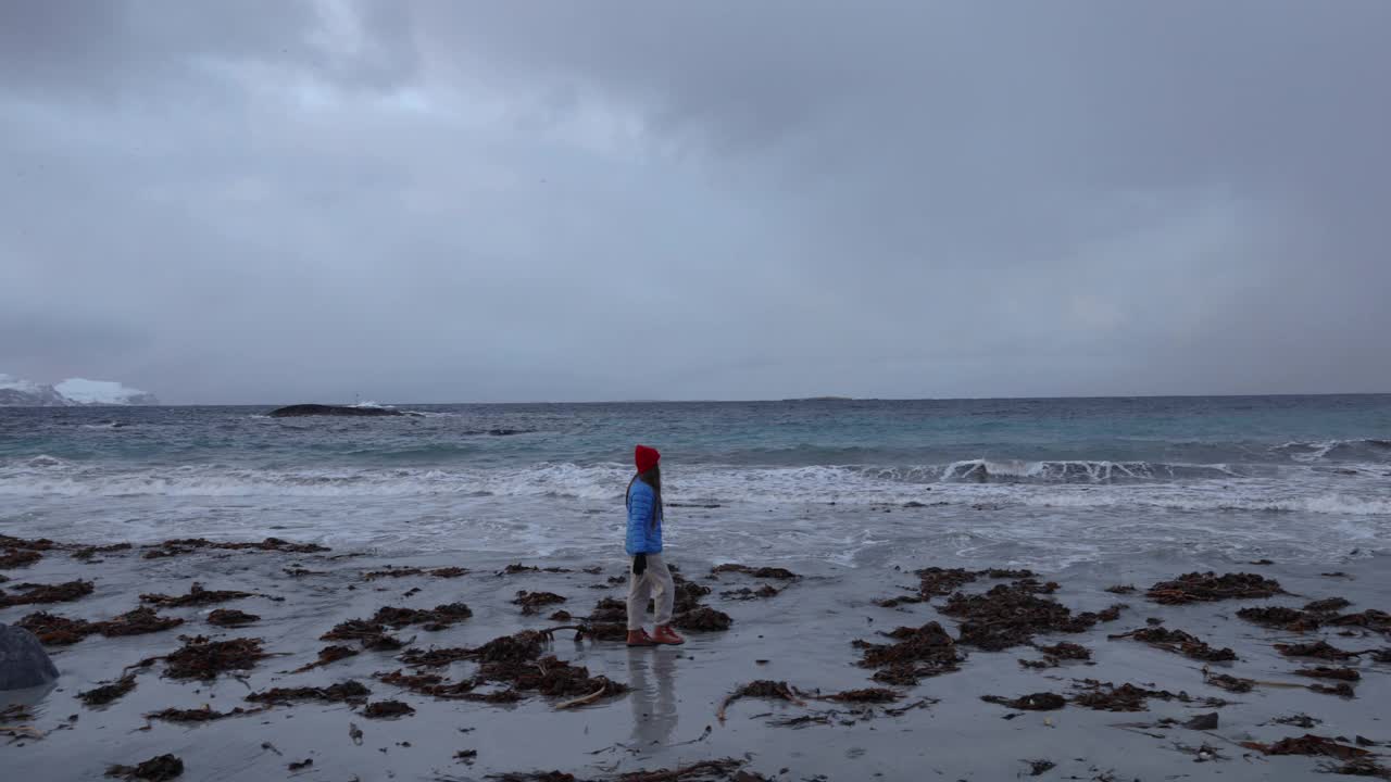 一个女人在挪威阴沉的海滩上思考冬日的一天视频素材