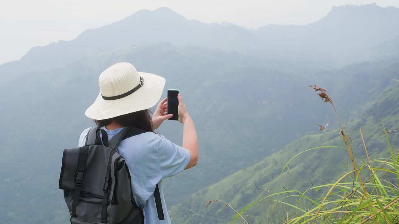 背着背包的女游客用智能手机拍摄山谷。视频素材