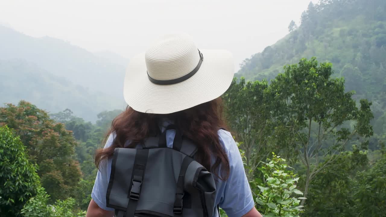 女游客带着帽子和背包在热带山区徒步旅行。视频素材