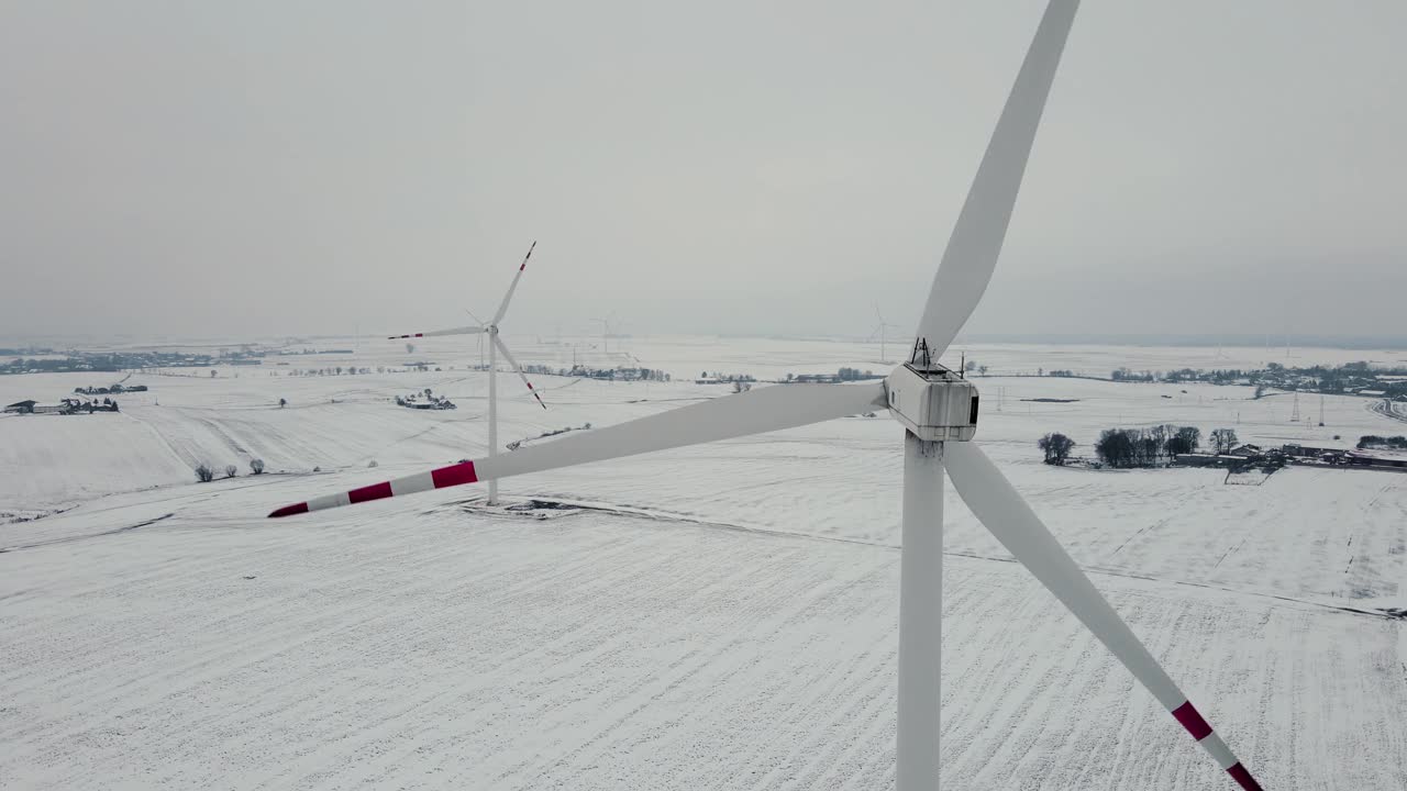 在寒冷的冰天雪地的冬季，风力旋转大型涡轮发电机叶片发电视频素材