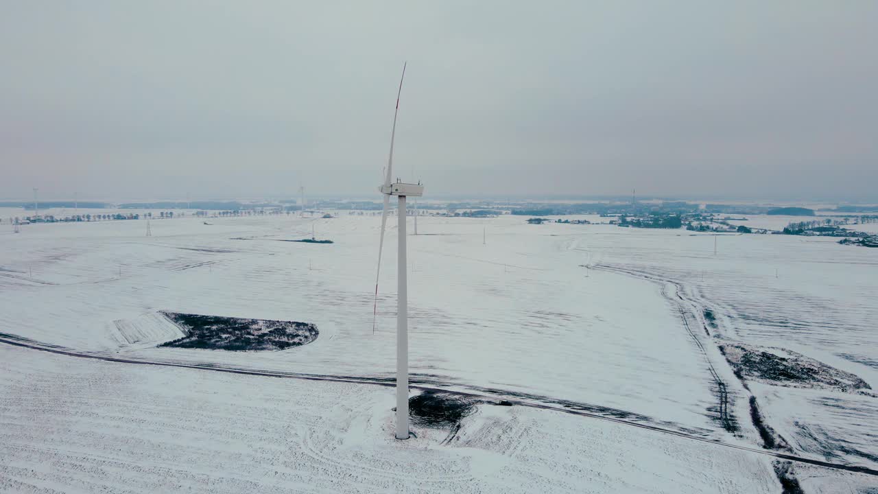 在寒冷的冰天雪地的冬天，涡轮机农场风车的鸟瞰图旋转视频素材