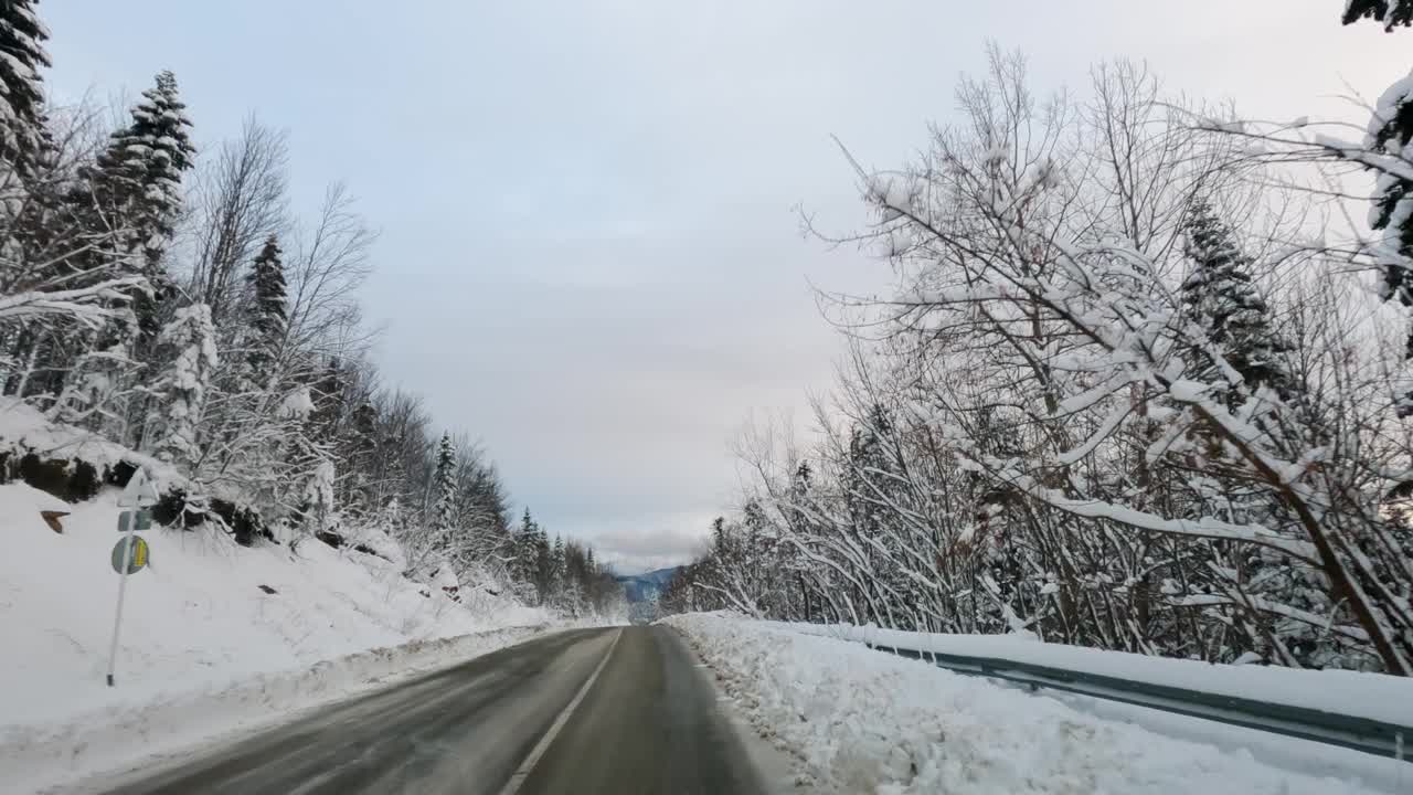 冬天积雪覆盖的道路在山林。射穿挡风玻璃。视频素材