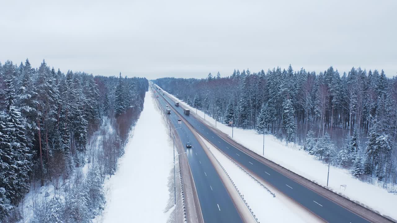 寒冷的冬天，汽车行驶在冰雪覆盖的树木和路边的高速公路上。视频素材