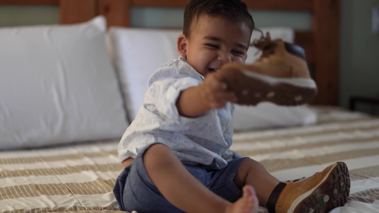 爸爸和妹妹在家里给蹒跚学步的孩子穿鞋视频素材