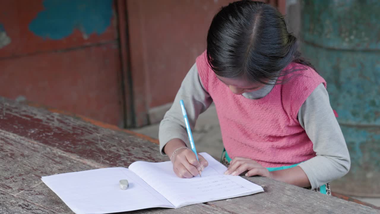 一个尼泊尔女孩在安纳普尔纳山脉附近的村庄里做作业视频素材