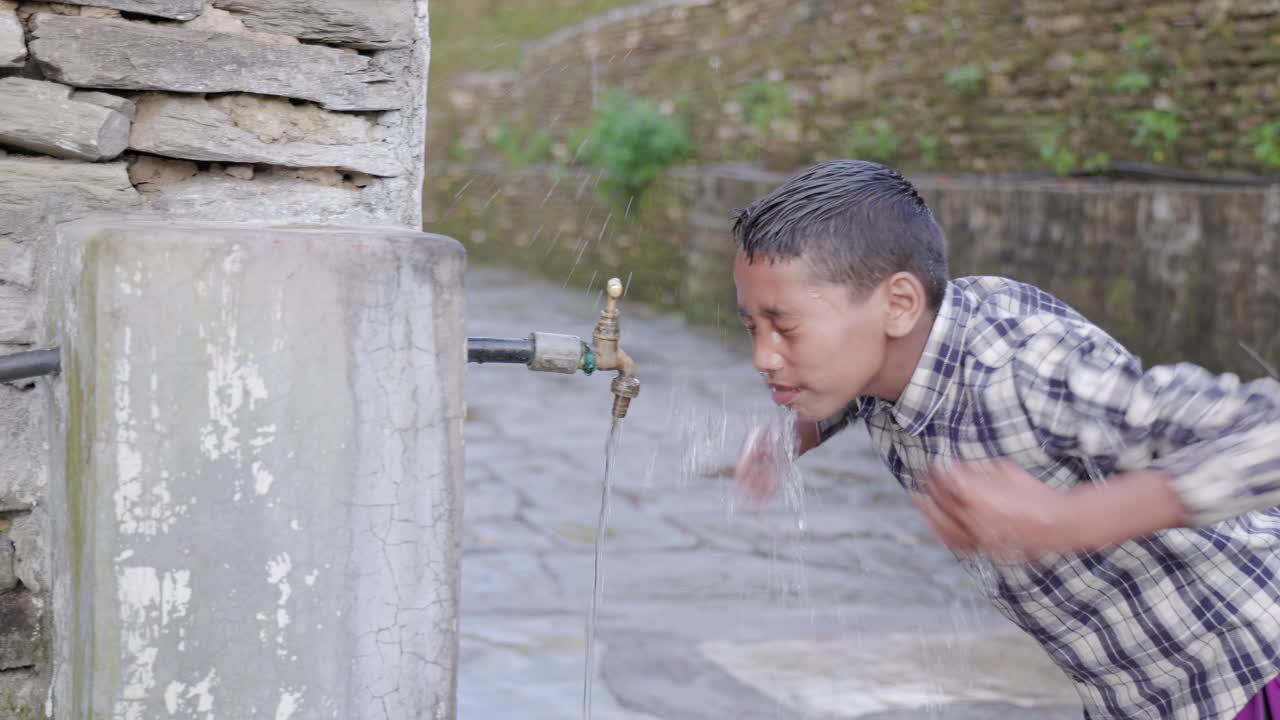 尼泊尔男孩在安纳普尔纳山脉附近的村庄里喝水视频素材