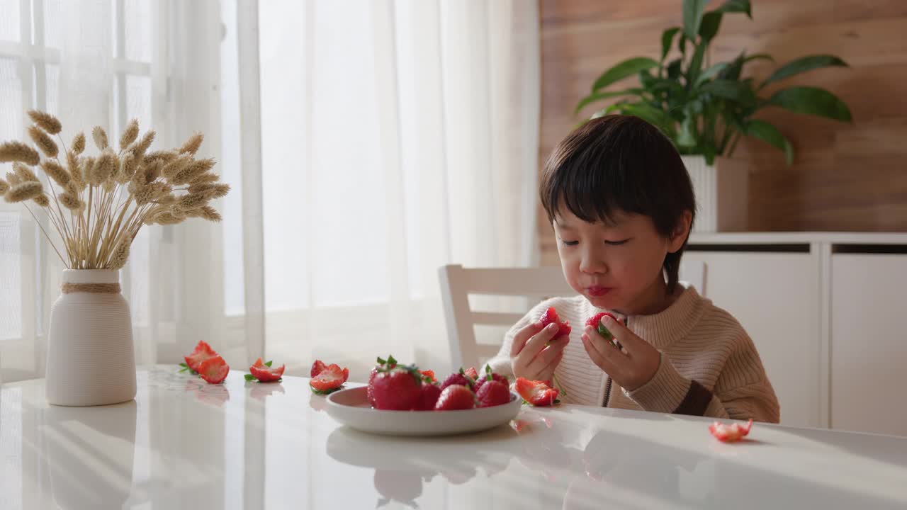 可爱的亚洲小孩在吃草莓视频素材