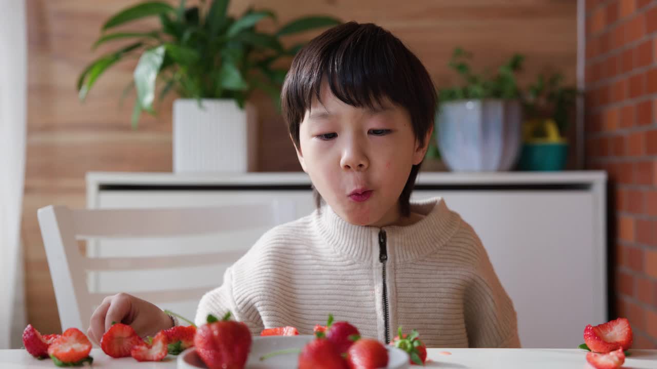 亚洲男孩在家里吃草莓视频素材