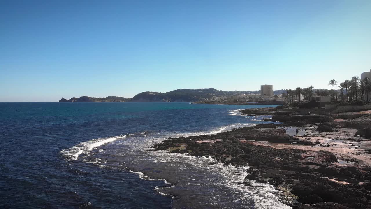 阳光明媚的夏日，西班牙科斯塔布兰卡的爪哇海岸线。美丽的海景，岩石海岸和背景上的建筑物。令人惊叹的自然景观视频素材