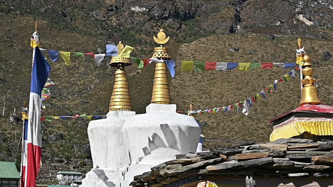 在尼泊尔昆布地区最大的夏尔巴人村庄Khumjung村的白色佛塔上，迎风飘扬的经幡。视频素材