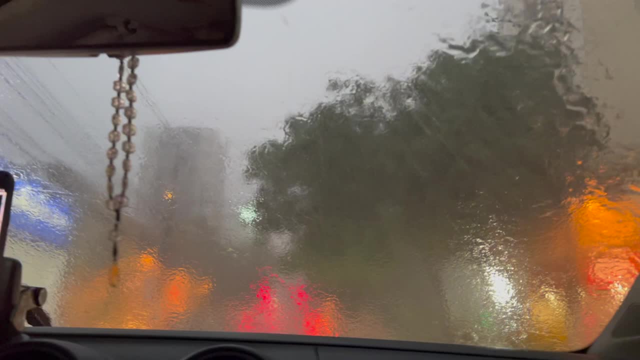 在大雨中开车。雨夜，玻璃上闪烁着灯光视频素材