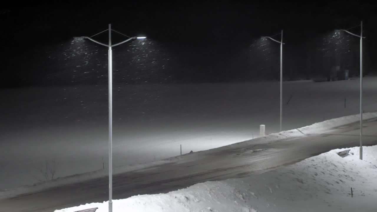 夜晚，路灯照亮了空荡荡的街道上的暴风雪视频下载