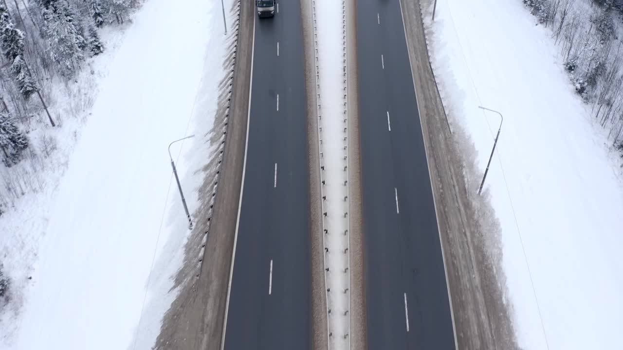 一辆卡车行驶在白雪覆盖的森林里的高速公路上。视频素材