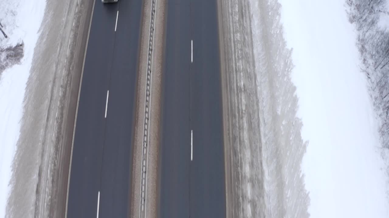 寒冷的冬天，汽车沿着公路行驶在白雪覆盖的森林中视频素材