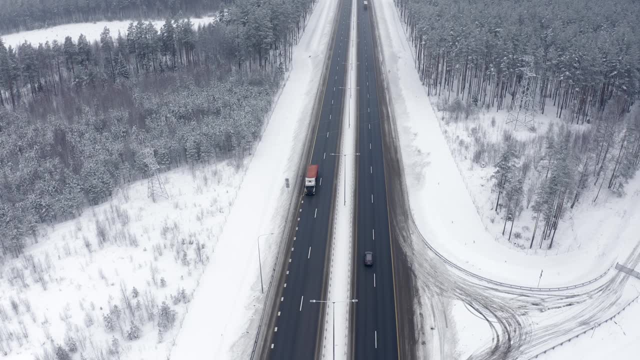 汽车在树枝上挂着雪的树林中行驶。视频素材