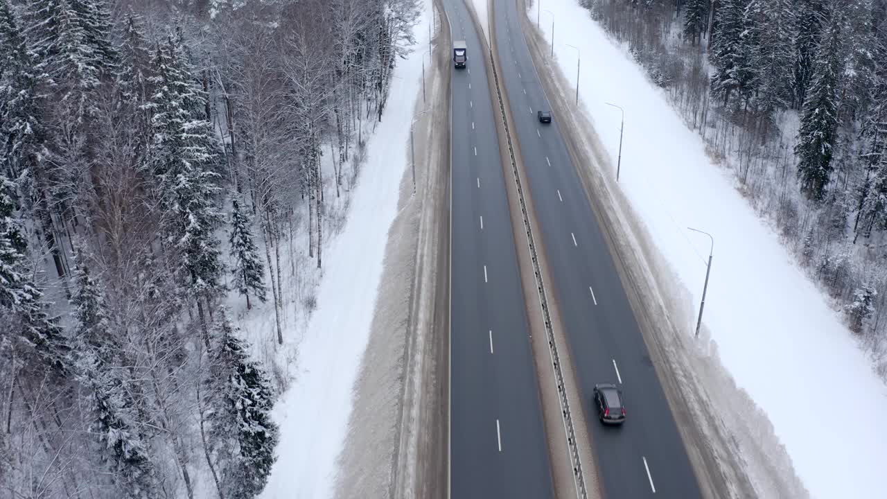 一辆黑色和银色相间的汽车行驶在白雪覆盖的森林中视频素材