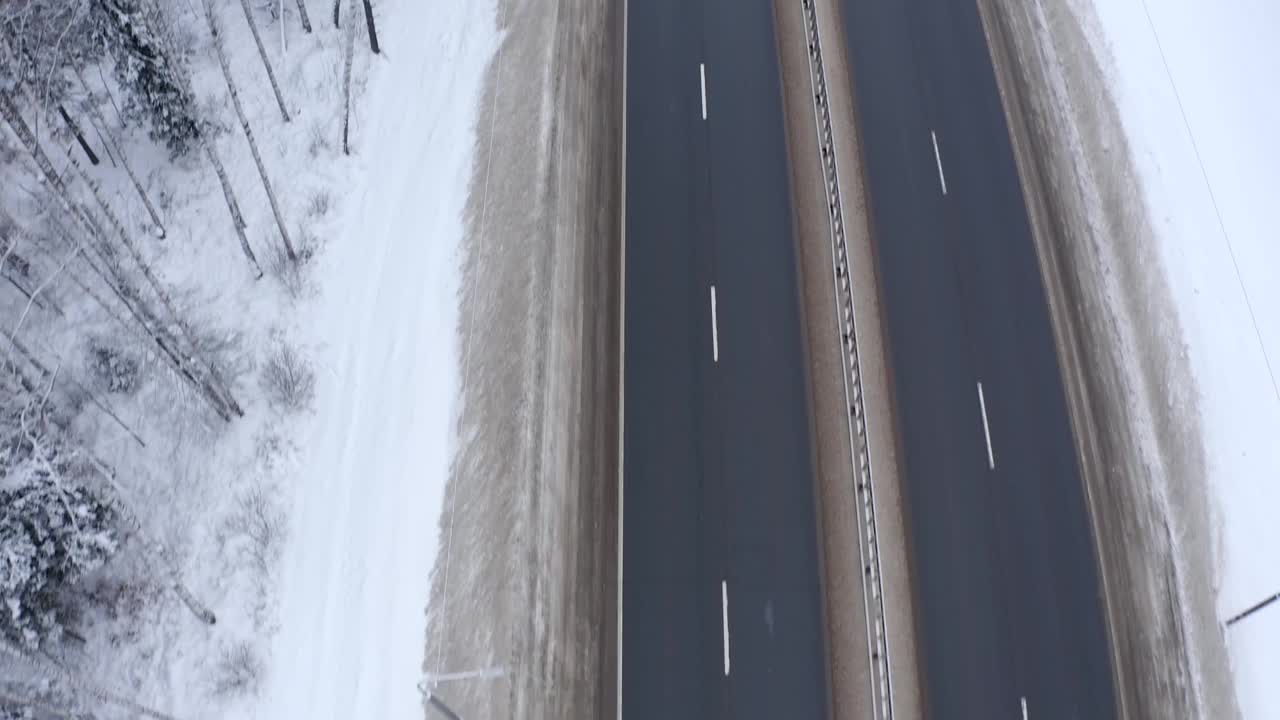 两辆卡车和一辆银色货车的屋顶沿着路边行驶，路边有雪和树。视频素材