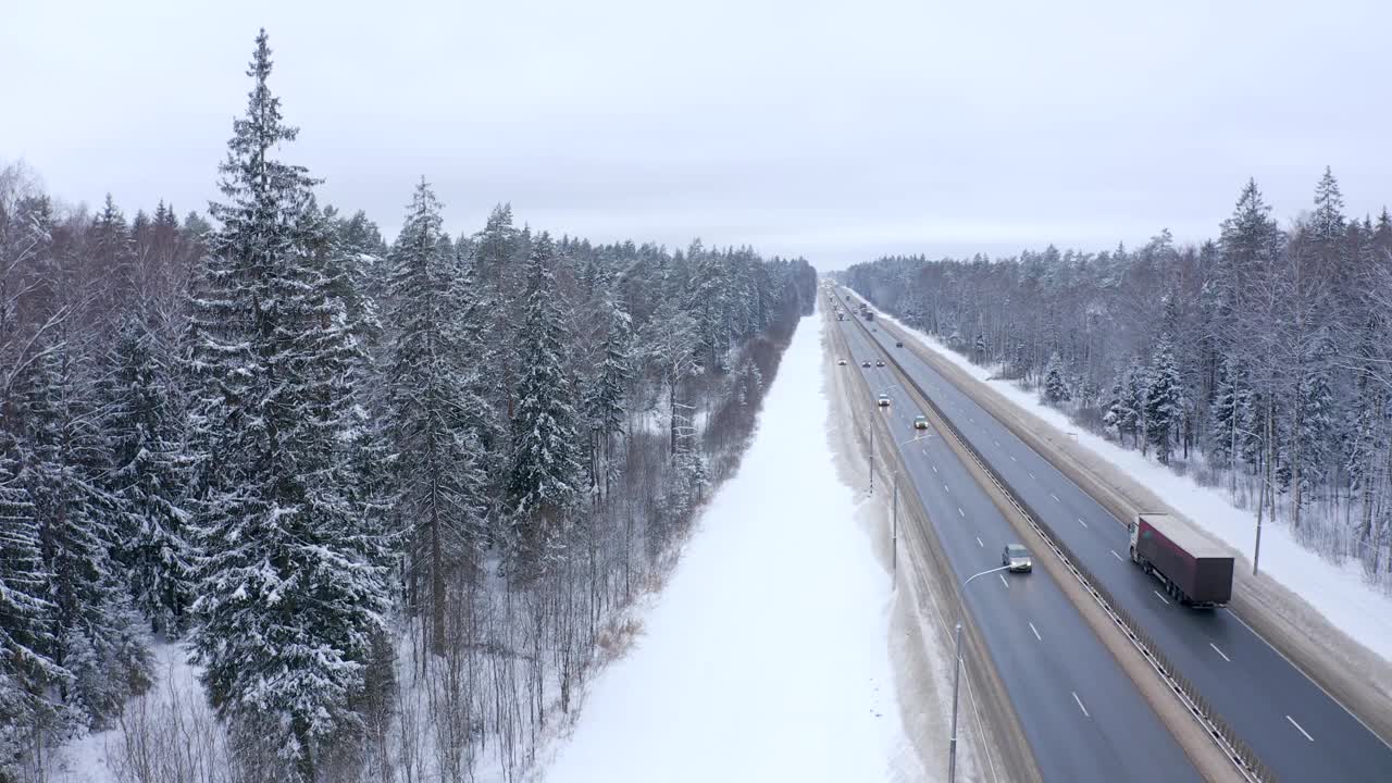 汽车和卡车在森林和被雪覆盖的路边通行视频素材