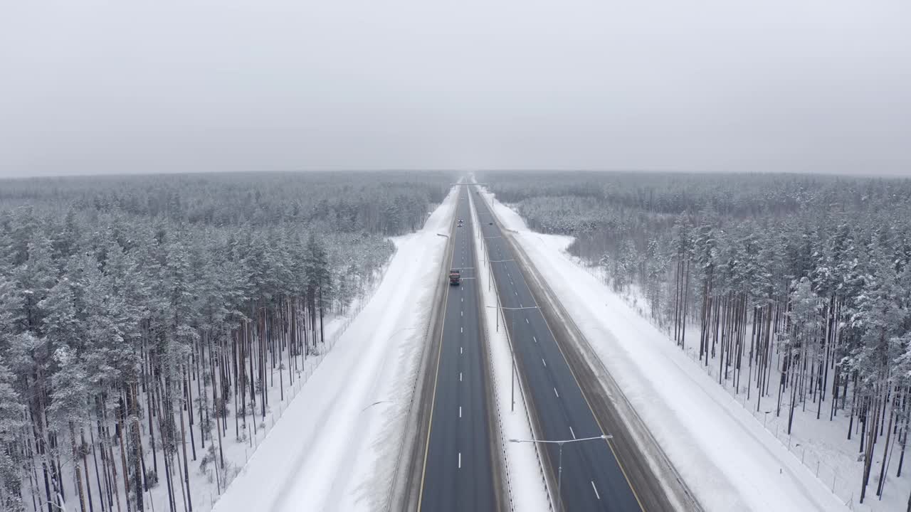 在寒冷的冬天，卡车在被积雪覆盖的树木之间运输货物视频素材