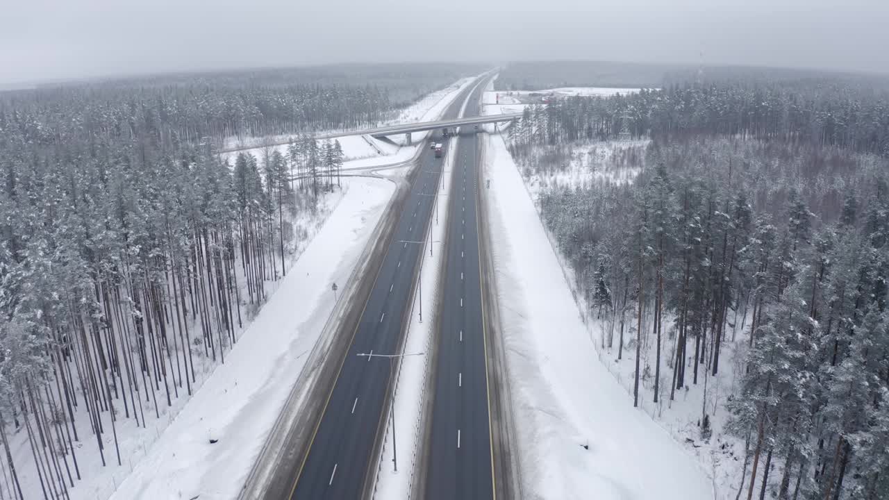 在一场严重的霜冻中，两辆卡车行驶在覆盖着积雪的森林中央的道路上。视频素材