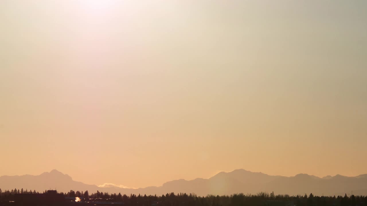 明亮的阳光日落时间流逝4k镜头。夏天黄色温暖的太阳。山上的日落。美丽的阳光散景光透镜耀斑照耀在日落在地平线上。视频素材