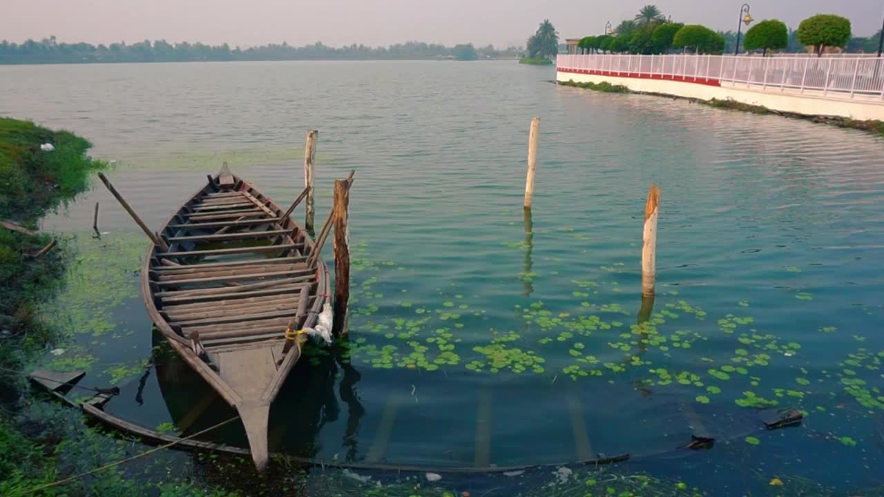 停泊在湖边的系泊或锚定的桨船另一艘船沉没或淹没在浅水中。视频素材