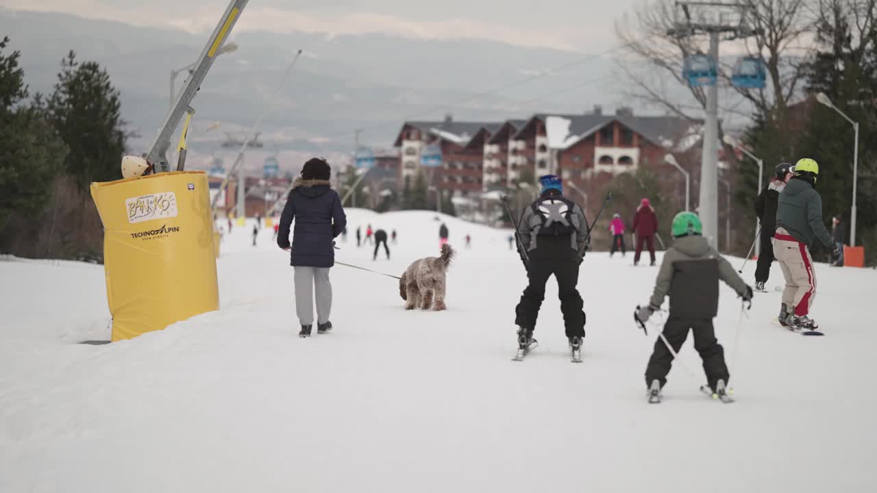 在保加利亚的班斯科，滑雪者和滑雪板人在滑雪坡上骑行，这是一个四季皆宜的度假胜地，慢镜头视频素材