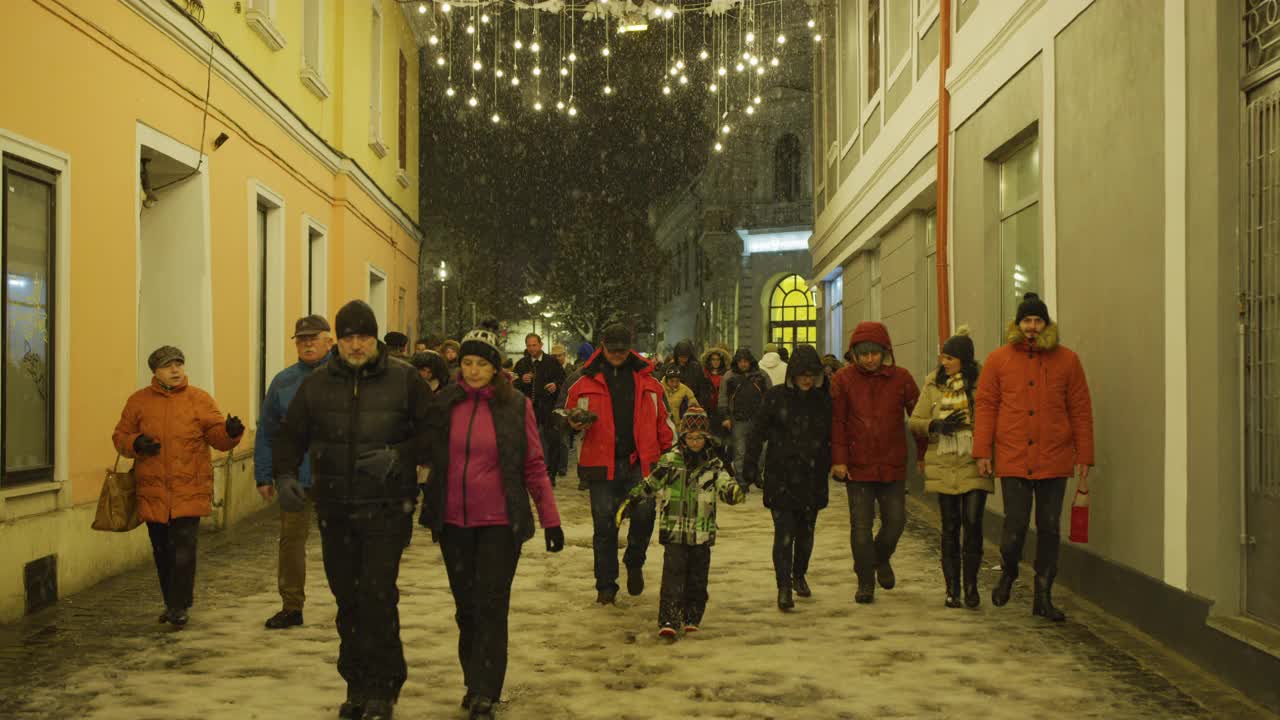 人们走在街上，在一个下雪的冬夜视频素材