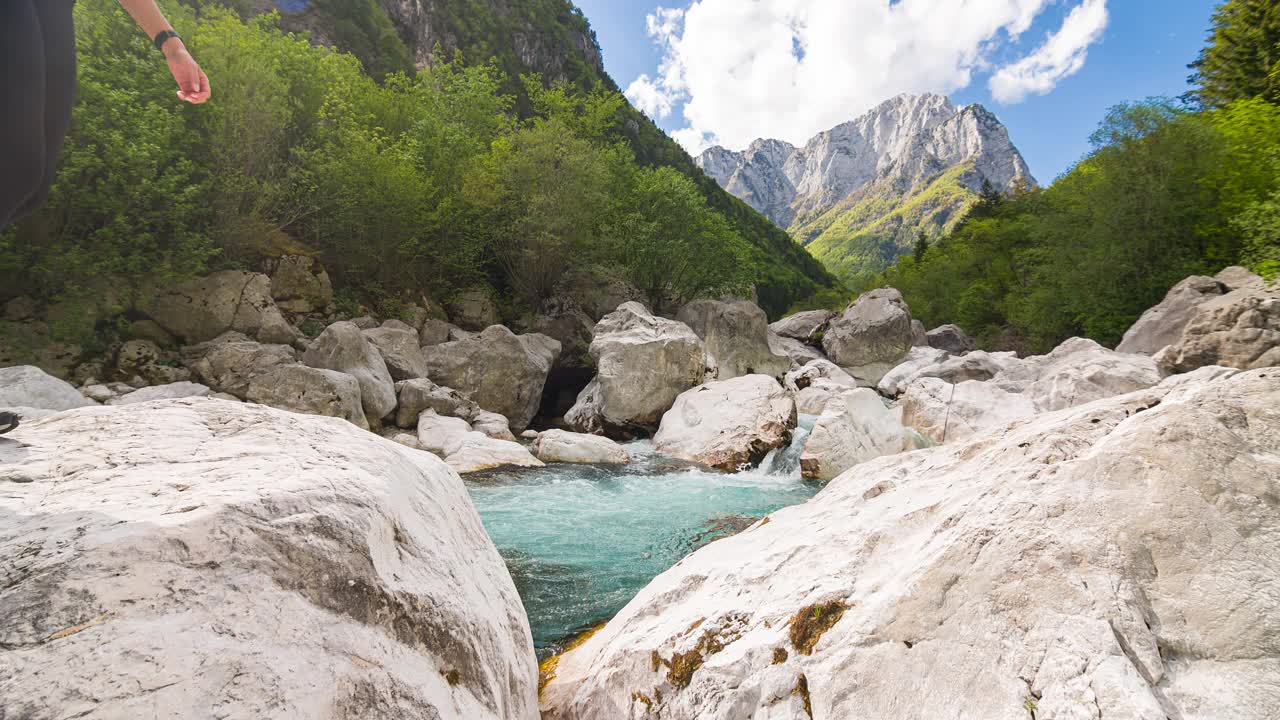 女徒步旅行者在山上过河，跳过水视频素材