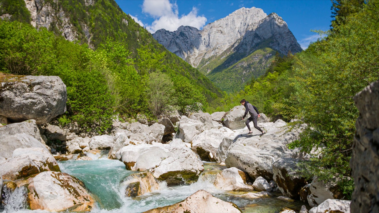 年轻人在壮丽的风景中跳过高山河流视频素材