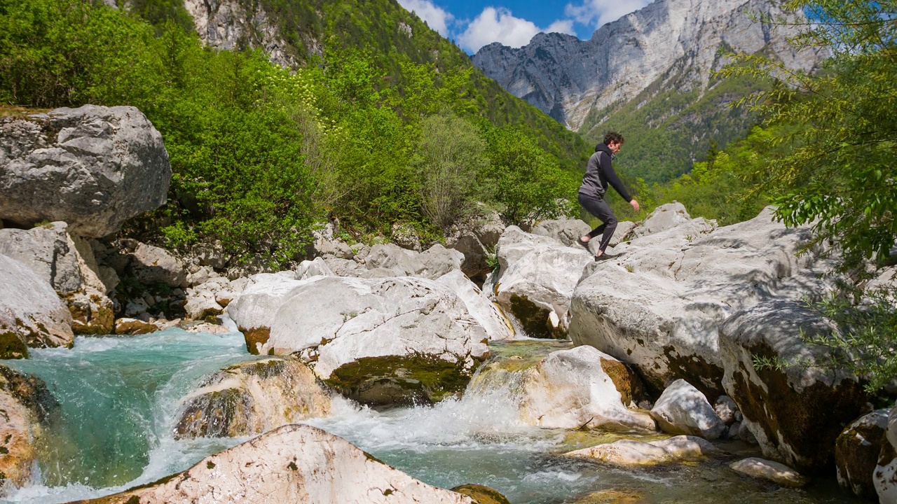 徒步旅行者越过河流在山上跳过水视频素材