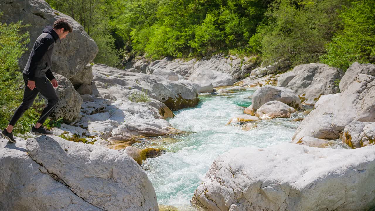 年轻人在壮丽的风景中跳过高山河流视频素材