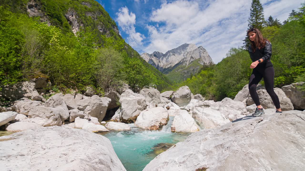 女徒步旅行者越过河流在山上跳过水视频素材