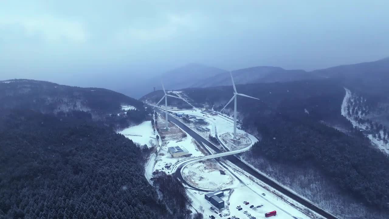 韩国江原道大关岭山口附近被雪覆盖的道路和风力发电机视频素材