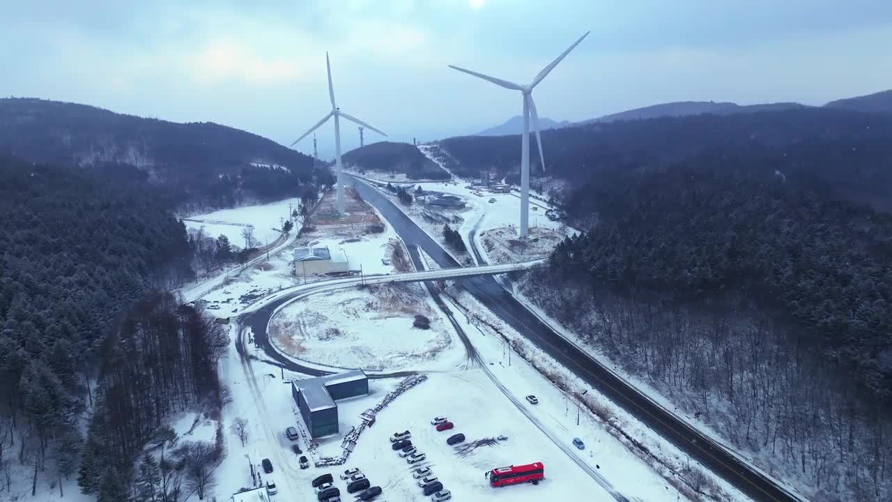 韩国江原道大关岭山口附近被雪覆盖的道路和风力发电机视频素材