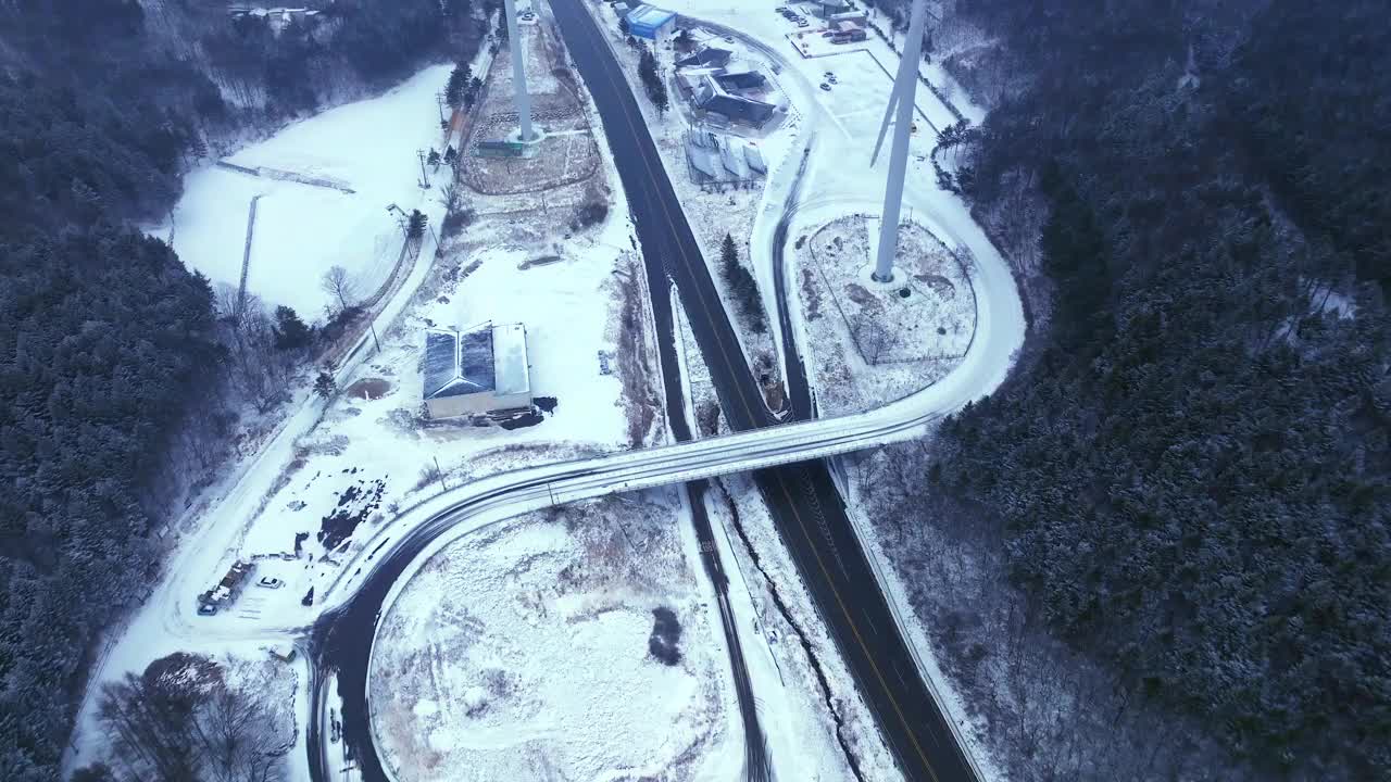 韩国江原道大关岭山口附近被雪覆盖的道路和风力发电机视频素材