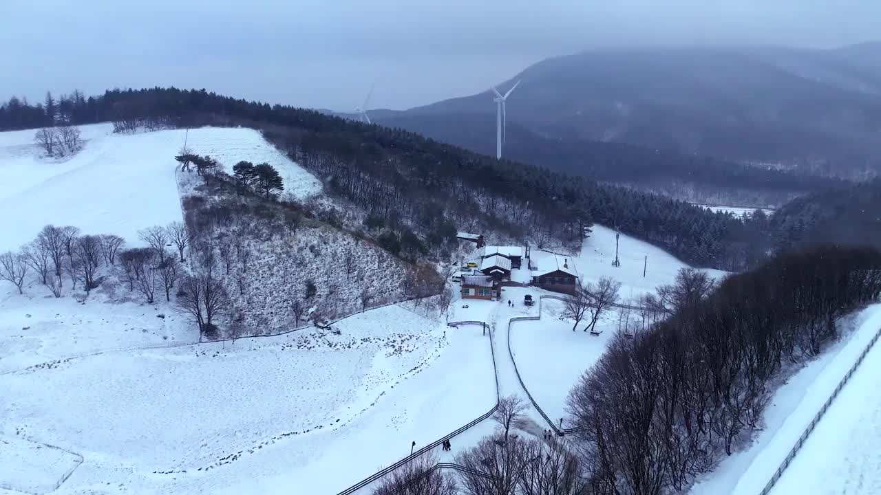 韩国江原道大关岭山口附近被雪覆盖的道路和风力发电机视频素材