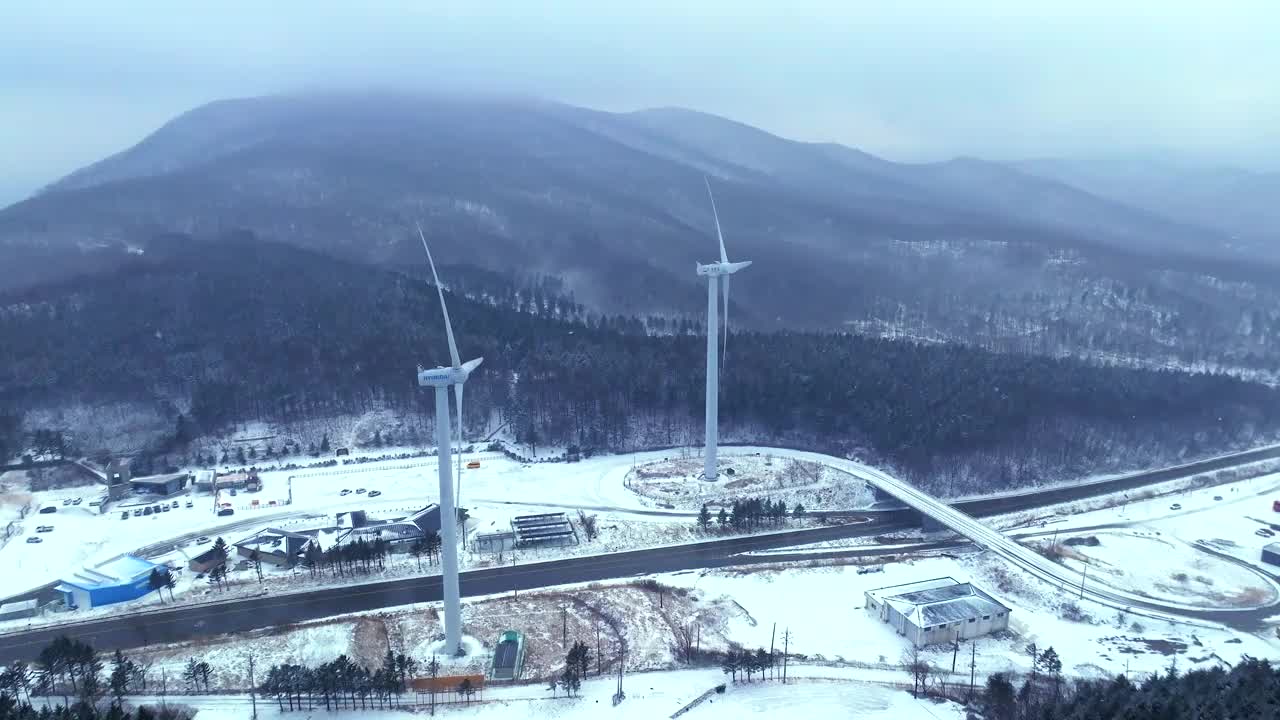 韩国江原道大关岭山口附近被雪覆盖的道路和风力发电机视频素材