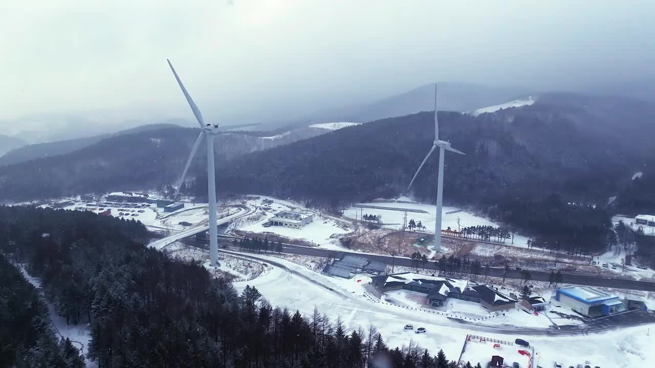 韩国江原道大关岭山口附近被雪覆盖的道路和风力发电机视频素材