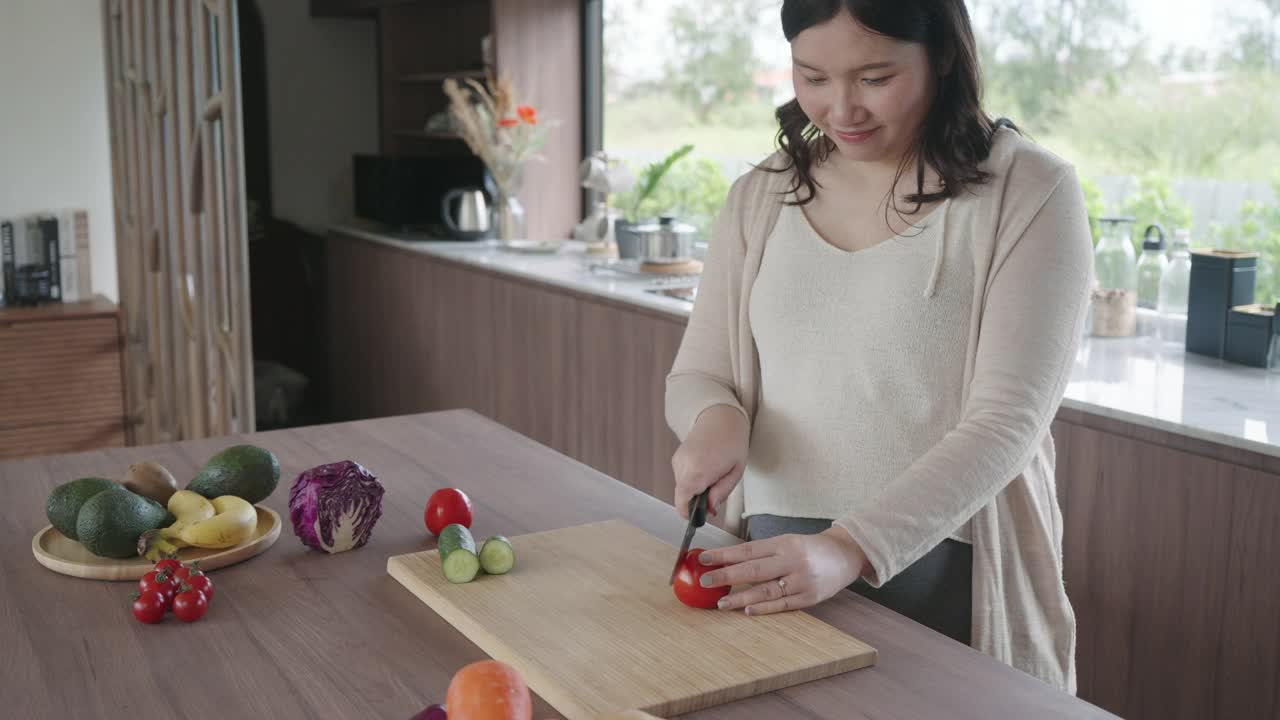 亚洲孕妇切西红柿做新鲜沙拉，女性在家准备美味的有机晚餐，为未来的母亲提供健康的营养视频素材