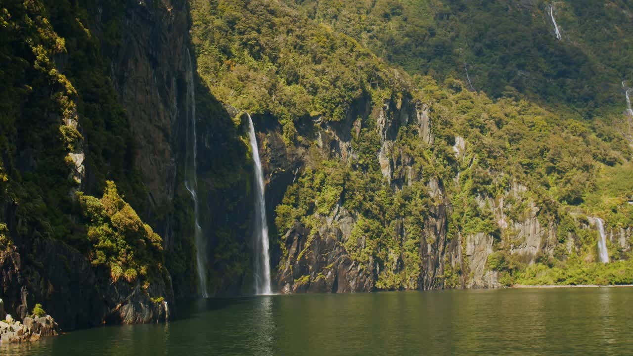 壮观的标志性景观，瀑布从米尔福德湾的山上流入海洋视频素材